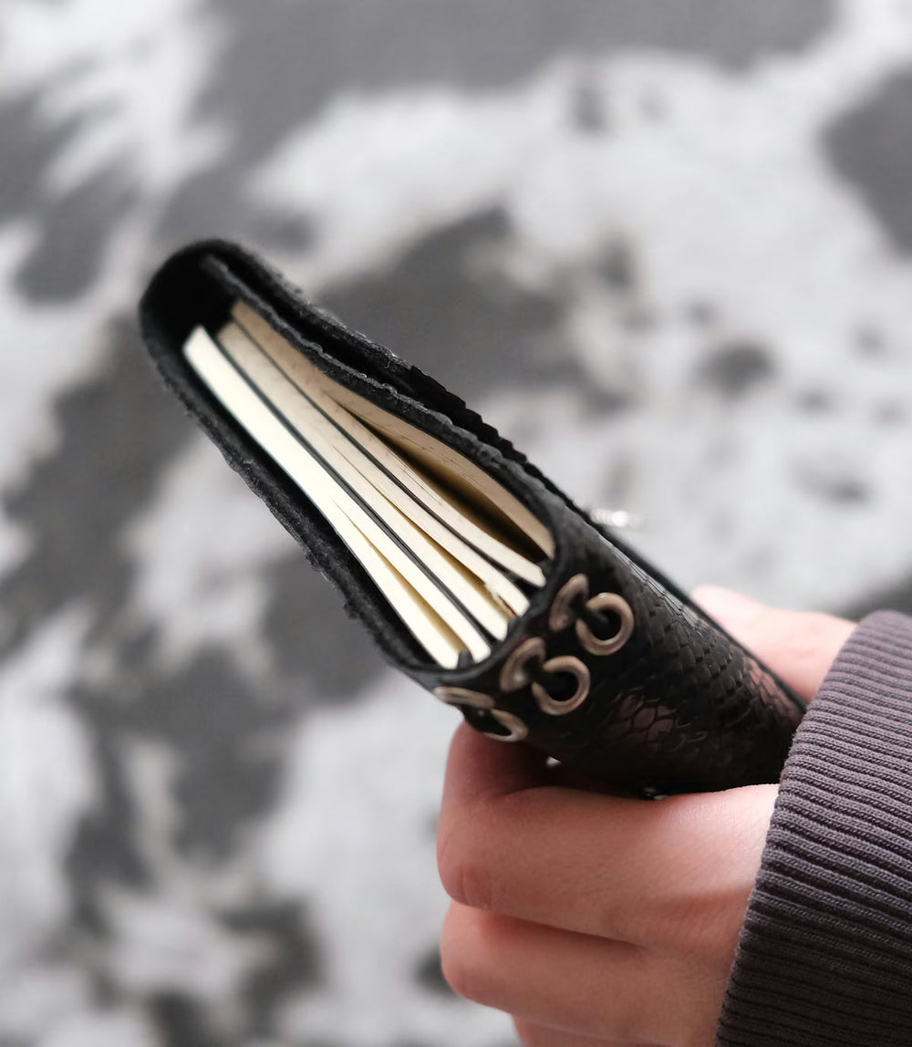Carnet d’écriture A6 en simili-cuir python noir tenu en main, idée cadeau pour une écrivaine