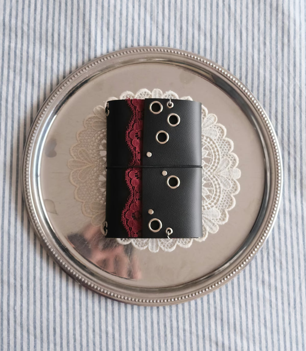 Carnet Lisse dentelle rouge A6 posé sur un plateau argenté et un napperon en dentelle