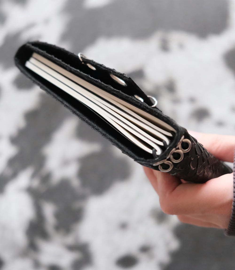 Carnet Python œillets cuivrés A5 tenu en main, vue de la tranche et des pages